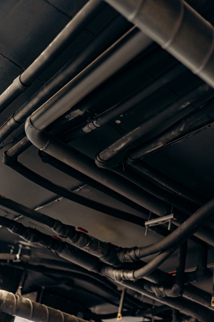 A vertical shot of industrial steel pipes and tubes in a dimly lit environment.